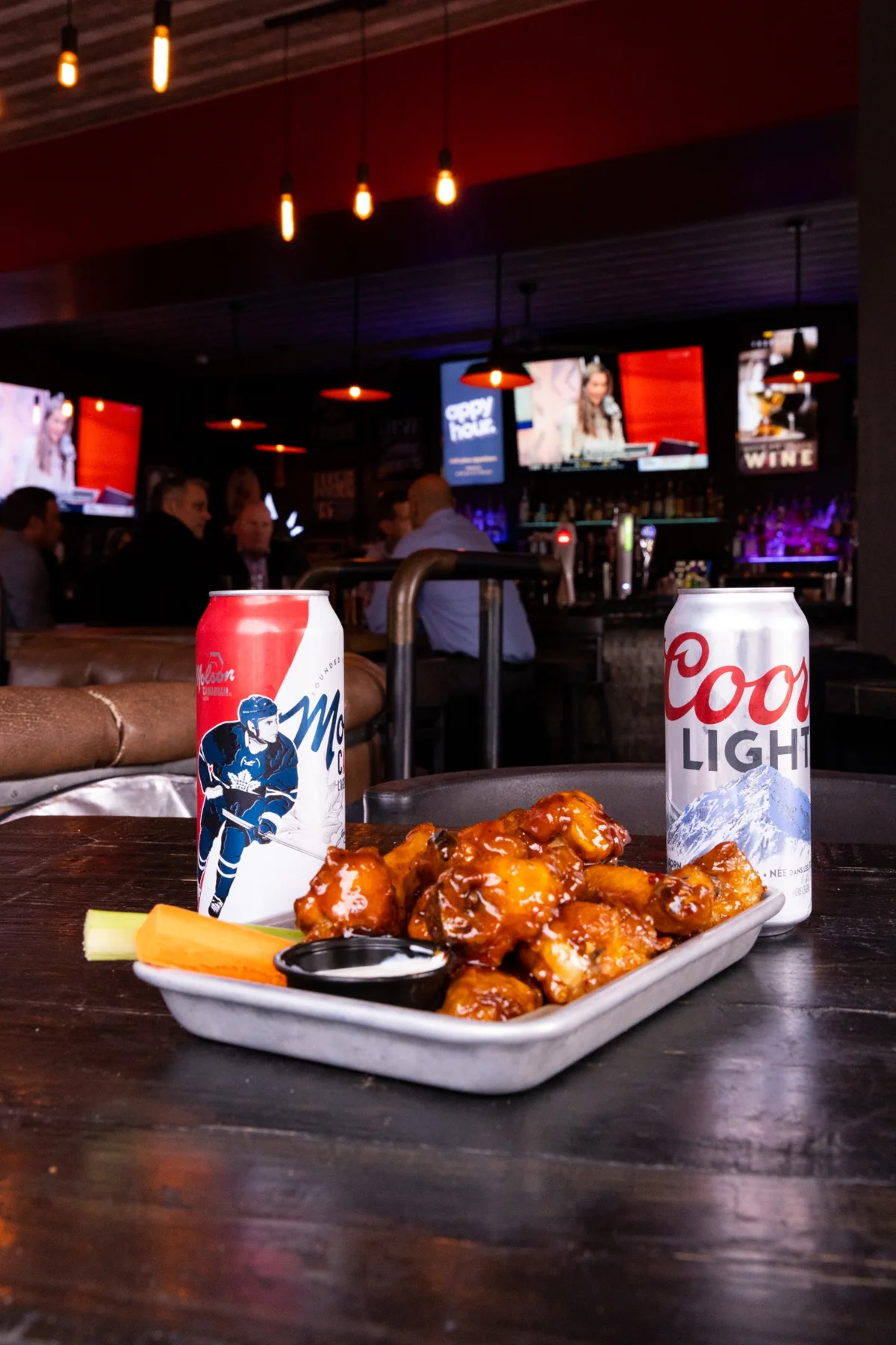 Sauced wings with cans of beer in the One Eighty bar